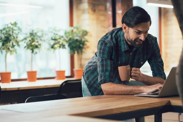 Handsome Mirthful Man Leaning Table Looking Laptop Screen While Standing — Stock Photo, Image