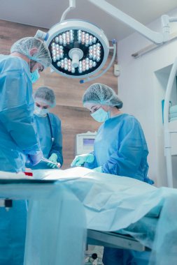 Steril üniformalı profesyonel tıp çalışanları cerrahi operasyonları yaparken birlikte dikkatli çalışıyorlar.