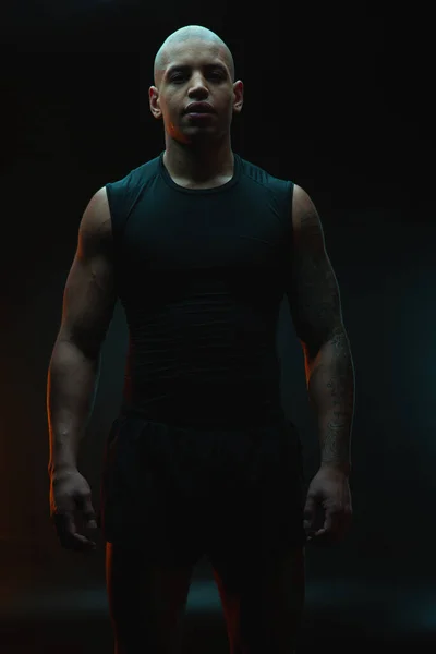 黒を背景に一人で立つ魅力的な筋肉入れ墨のスポーツマン — ストック写真