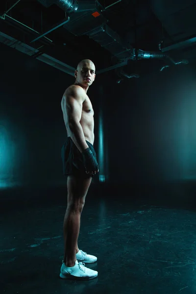手にボクシングの包帯で一人で立っている間 距離を調べるハンサムな若い筋肉の男 — ストック写真