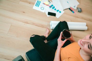 Bir bardak kahveyle rahatlamış gülümseyen bir kadının manzarası. Kattaki grafikler