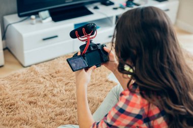 Uzun saçlı bir kızın elinde mikrofonla yatakta otururken çekilmiş bir fotoğrafı.