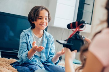 Arkadaşı önünde mikrofonlu bir kamera tutarken olumlu çocuk internette röportaj yapıyor.