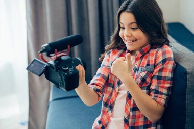 Kanepede oturan ve kendini mikrofonla kameraya kaydeden tatlı bir kız.