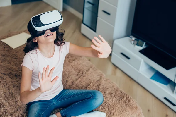 Yüzünde sanal gerçeklik cihazıyla yatakta otururken mutlu bir kız gerçek dışı bir şeye dokunuyor. Şablon pankartı