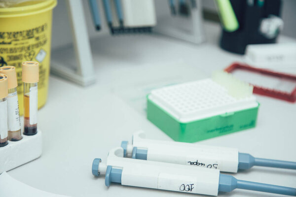 Close up of two labeled manual pipettes lying on the table near the test tube rack