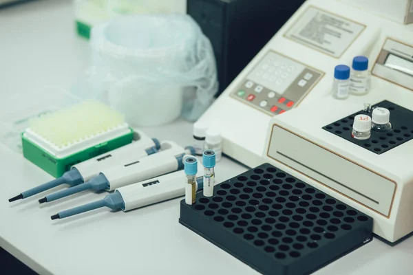 White table surface with three automatic pipette dispensers placed near the test tube rack