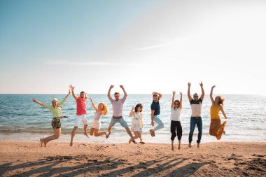 gençlerin grup kumsalda güzel yaz günbatımı üzerinde atlama mutlu. Dokuz kişi, beş kadın ve dört erkek. Arkadaşları ve tatil kavramı 