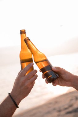 Şerefe! Sahilde bira şişesi ile toasting el kapatın. Kutlama kavramı