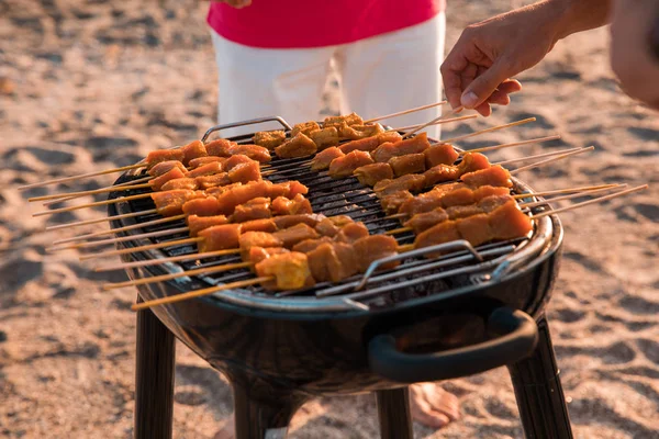 close up of people preparing a barbecue on the beach at sunset. Summer time concept