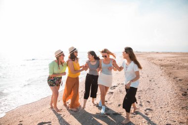 Group of women friends having fun and dancing on the beach. Holiday concept clipart