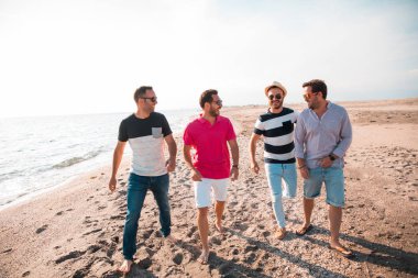 Güzel yaz günbatımında sahilde yürüyen bir grup mutlu genç. Arkadaşlar ve tatil konsepti