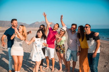Multicultural group of friends partying on the beach - Young people celebrating during summer vacation, summer time and holidays concepts clipart