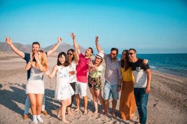 Multicultural group of friends partying on the beach - Young people celebrating during summer vacation, summer time and holidays concepts clipart