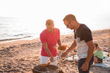 Mutlu arkadaşlar sahilde barbekü hazırlarken eğleniyorlar. Tatil kavramı.