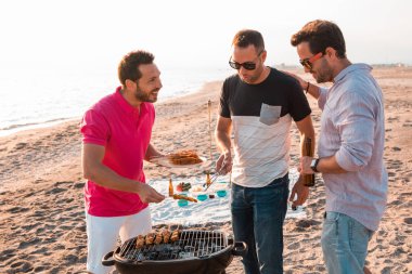 Sahilde Barbekü hazırlanıyorlar iken mutlu arkadaşlar eğlenmeye mı. Tatil kavramı.