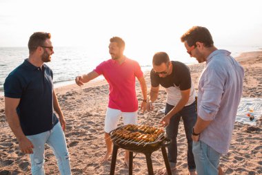 Sahilde Barbekü hazırlanıyorlar iken mutlu arkadaşlar eğlenmeye mı. Tatil kavramı.