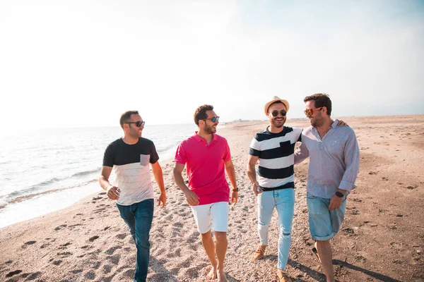 Group of happy young people walking at the beach on beautiful summer sunset. Friends and holiday concept