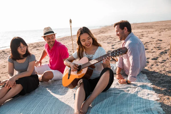 Multicultural group of friends partying on the beach - Young people celebrating during summer vacation, summertime and holidays concepts