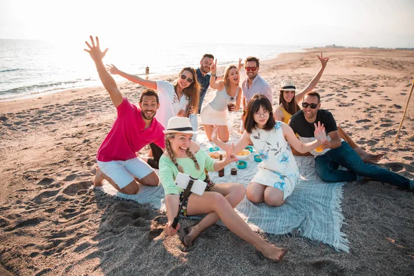 Multicultural group of friends partying on the beach  happy young people celebrating during summer vacation. summer time and holidays concepts.