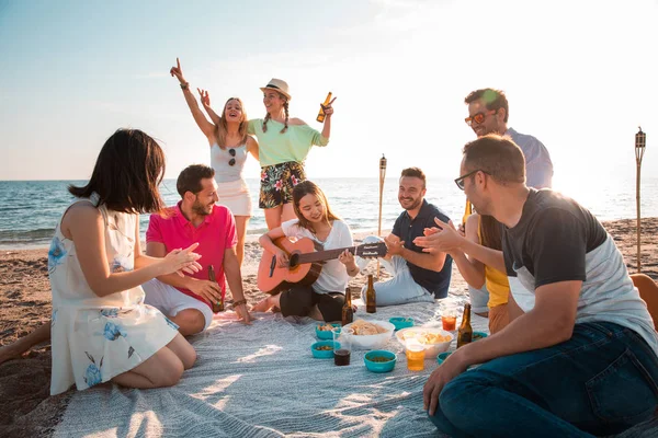 Multicultural group of friends partying on the beach  happy young people celebrating during summer vacation. summer time and holidays concepts.