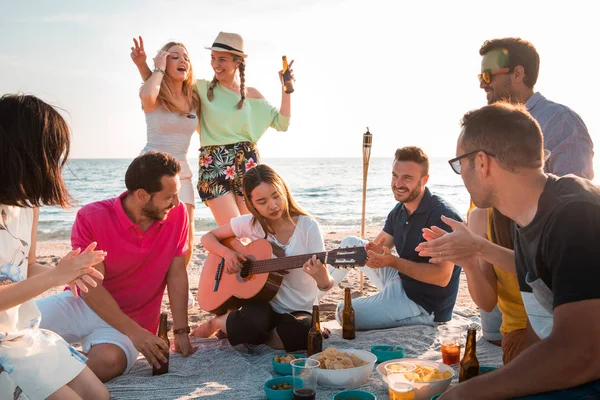 Multicultural group of friends partying on the beach  happy young people celebrating during summer vacation. summer time and holidays concepts.