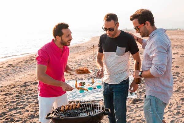 Sahilde Barbekü hazırlanıyorlar iken mutlu arkadaşlar eğlenmeye mı. Tatil kavramı.