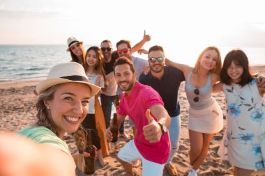 Happy multiracial young people are making a selfie at the beach while they are in a summer party. Friends and holiday concept clipart