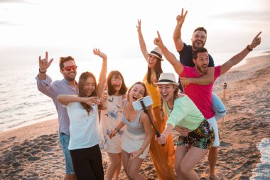 Happy multiracial young people are making a selfie at the beach while they are in a summer party. Friends and holiday concept clipart