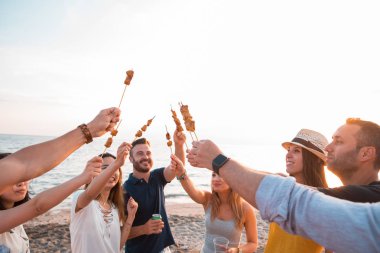 Mutlu arkadaş akşam yemeği sahilde Barbekü pişmiş bir brochette. Yaz saati ve tatil kavramı.