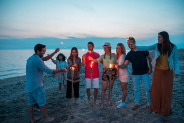 Mutlu arkadaş onların maytap sahilde bir parti sırasında aydınlatma grubu. Yaz saati.