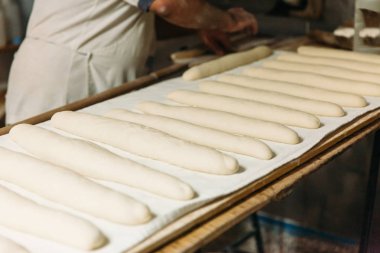 Baker ahşap bir fırında pişirme önce çiğ hamur ekmek hazırlanıyor. Geleneksel ekmek kavramı.