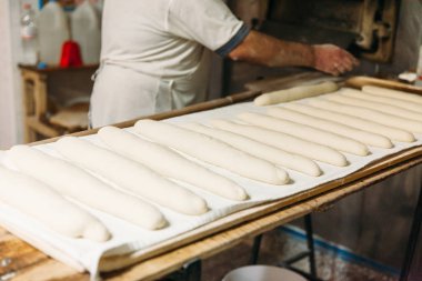 Baker ahşap bir fırında pişirme önce çiğ hamur ekmek hazırlanıyor. Geleneksel ekmek kavramı.