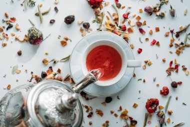 Çay molası zamanı. Birisi bir çaydanlık beyaz masa arka plan üzerine bir bardak çay atarak düz lay.