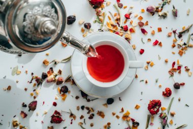 Çay molası zamanı. Birisi bir çaydanlık beyaz masa arka plan üzerine bir bardak çay atarak düz lay.