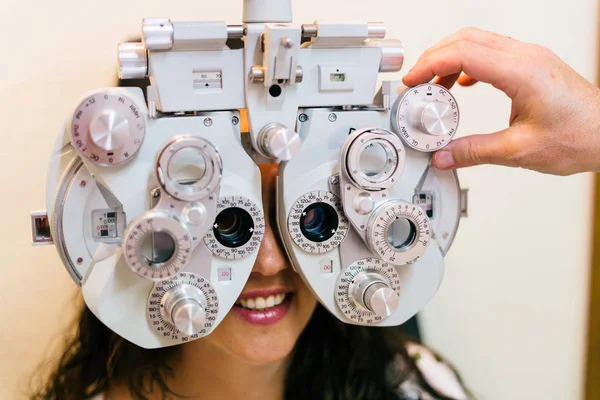 Smiling woman doing eyesight measurement with optical phoropter