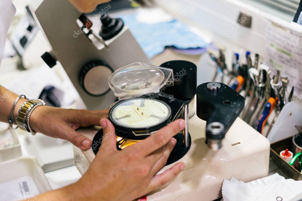 Female optician measuring and preparing glasses on the latest digital device in optical store. Professional ophthalmology instrument in clinic office and optics