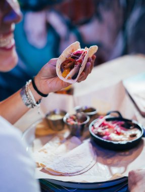 Hazırlama ve sokak bir restoranda Meksika yemeği yeme genç kadın. Meksika tacos, cips ve kanatlar.