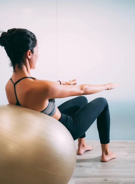 Woman working out with exercise ball in gym. Pilates woman doing exercises in the gym workout room with fitness ball. Fitness woman doing exercises for muscle press with abs swiss ball.