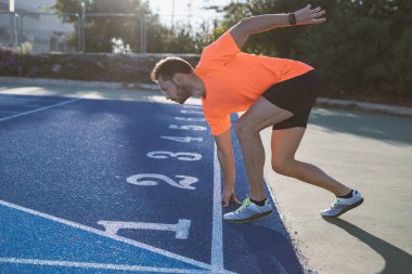 Başlama pozisyonu bir yarış başlamak için hazır, genç sporcu adam. Taslakları yarış pisti üzerinde yarış için hazır.