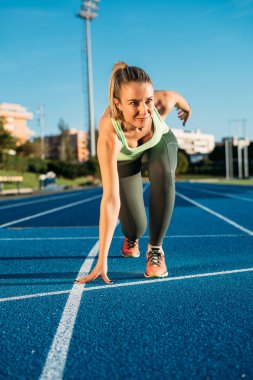 Başlama pozisyonu bir yarış başlamak için hazır, genç sporcu kadın. Taslakları yarış pisti üzerinde yarış için hazır.