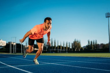 Genç sporcu adam bir başlangıç konumu bir yarışta çalışmasına başlamak üzere. Adım başlamak 