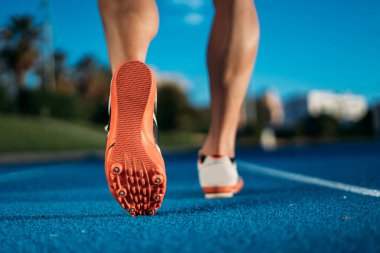 Adam mavi yarış pisti üzerinde başlangıç satırından başlamak üzere çalışan ayak arkadan görünüm