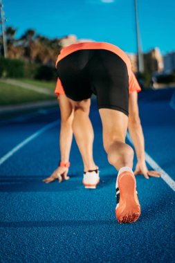 Arkadan görünüşü üzerinde mavi koşu parkuru başlayan genç bir erkek atlet