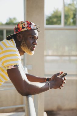 Yakışıklı siyah adam cep telefonunu kullanıyor.