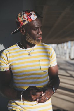 Yakışıklı siyah adam cep telefonunu kullanıyor.