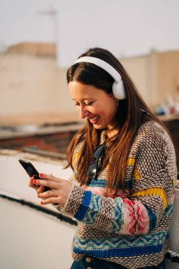 Genç kadın çatı üzerinde kulaklık ile müzik dinlemek