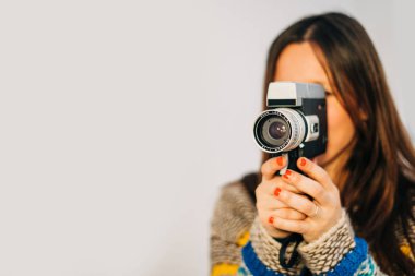 Kırmızı dudaklı beyaz bir arka plan üzerinde izole retro bir video kamera ile genç gülümseyen kadın