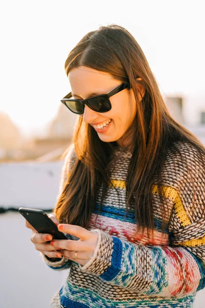 Jovem Mulher Sorridente Com Óculos Sol Usando Seu Smartphone Terraço — Fotografia de Stock