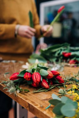 Adam çiçekçi kırmızı lale çiçek buketi ahşap masaya sağlar.